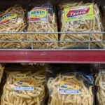 Delapan bungkus plastik camilan stik keju buatan usaha rumahan tersusun di rak toko berpalang merah