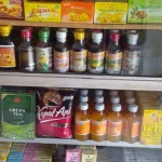Rak kaca sebuah warung di Kebumen berisi jamu kemasan, madu botolan, vitamin C sachet, teh, kopi, dan susu kotak